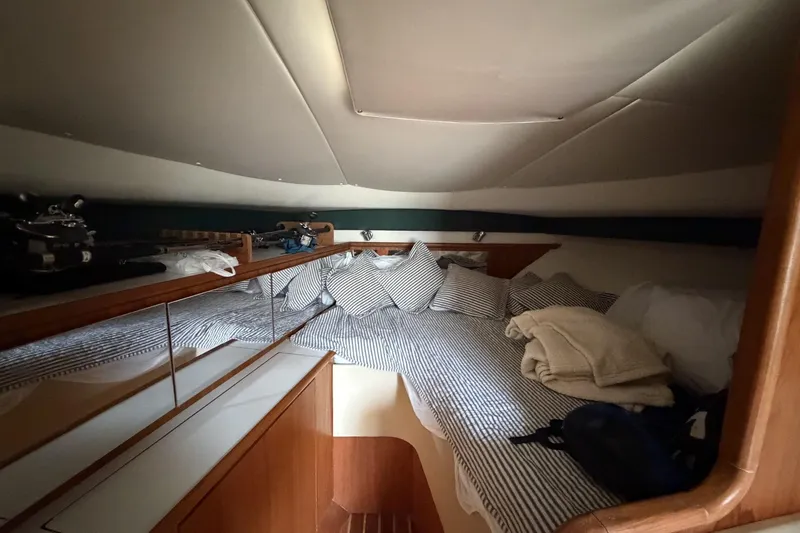 Slide: The Image of Cozy cabin interior of 1998 Pursuit 3400 Express with striped bedding and wooden accents. - 24