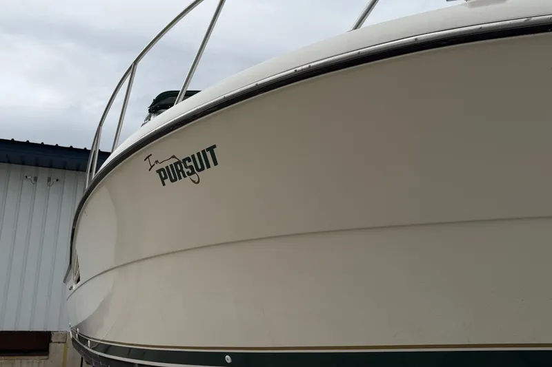 Slide: The Image of 1998 Pursuit 3400 Express boat with sleek design, docked near a building. - 4