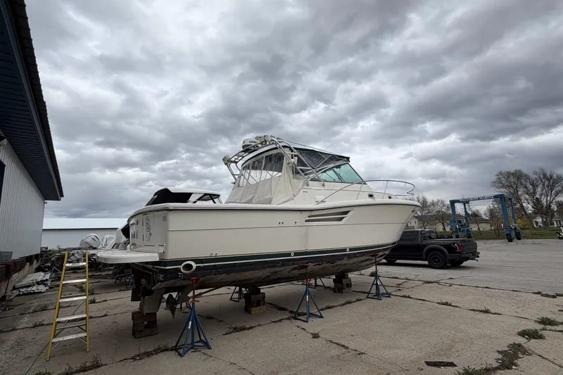 Slide: The Image of 1998 Pursuit 3400 Express boat on stands, overcast sky, marina setting. - 6