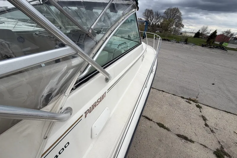 Slide: The Image of 1998 Pursuit 3400 Express boat docked on concrete under cloudy skies. - 8