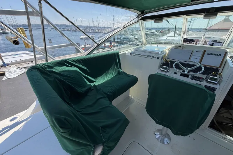 Slide: The Image of 1998 Pursuit 3400 Express boat cockpit with green covers, overlooking marina. - 13