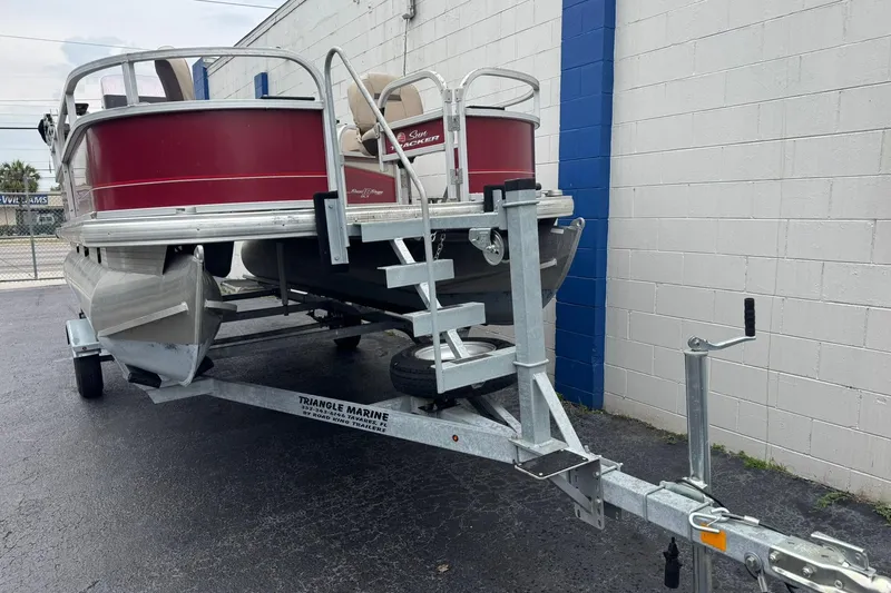 Slide: The Image of 2019 Sun Tracker Bass Buggy 18 DLX pontoon boat on trailer, parked by a building. - 4