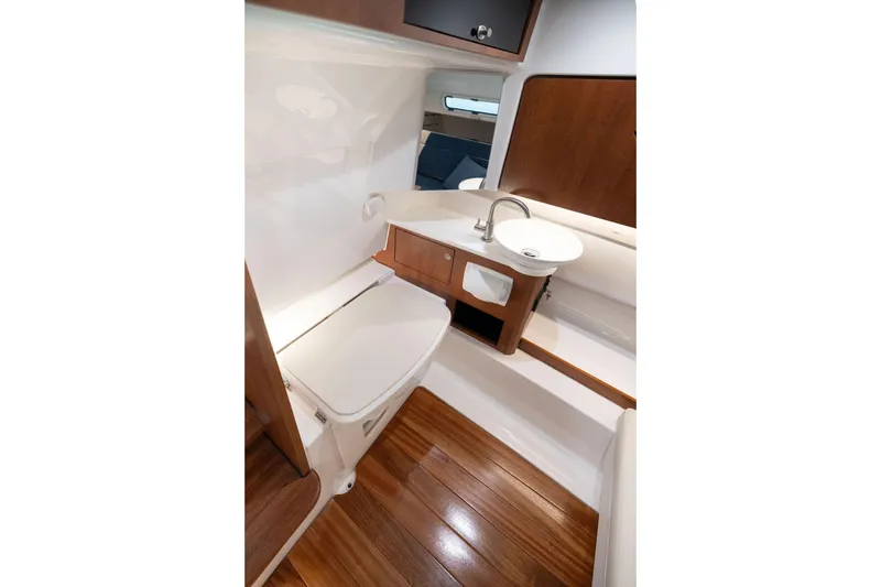 Slide: The Image of 2026 Pursuit S 328 Sport boat interior with wooden flooring and compact bathroom amenities. - 33