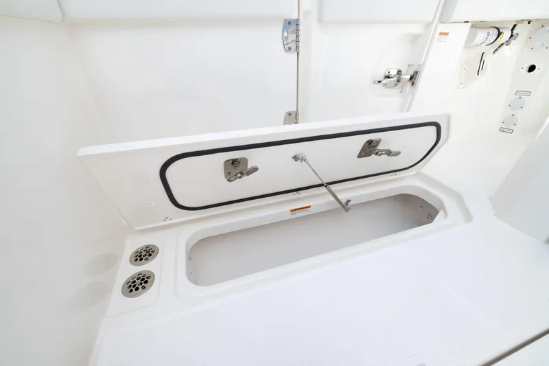 Slide: The Image of 2026 Pursuit S 328 Sport boat storage compartment with open hatch and drainage system. - 6