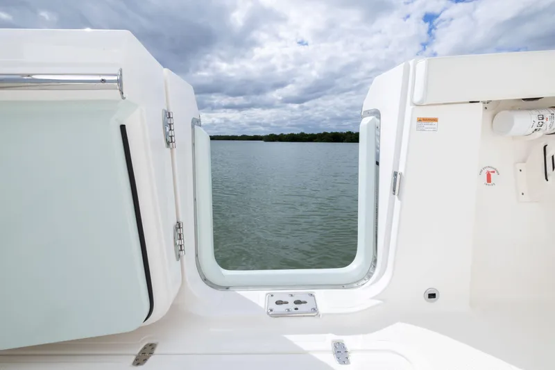 Slide: The Image of 2026 Pursuit S 328 Sport boat with open door, overlooking serene water and cloudy sky. - 7
