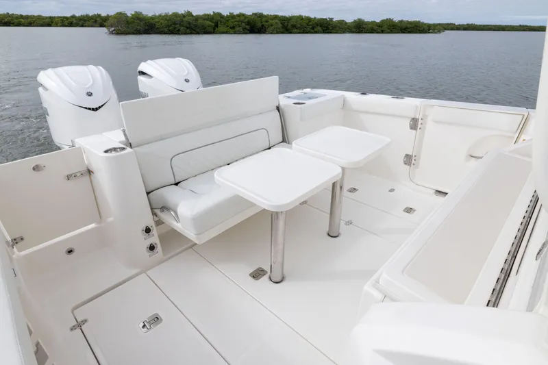 Slide: The Image of 2026 Pursuit S 328 Sport boat interior with seating and dual outboard engines on a calm lake. - 8
