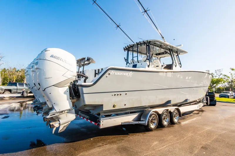 Slide: The Image of 2022 Freeman 42LR boat with dual Mercury engines on a trailer, under clear blue sky. - 69