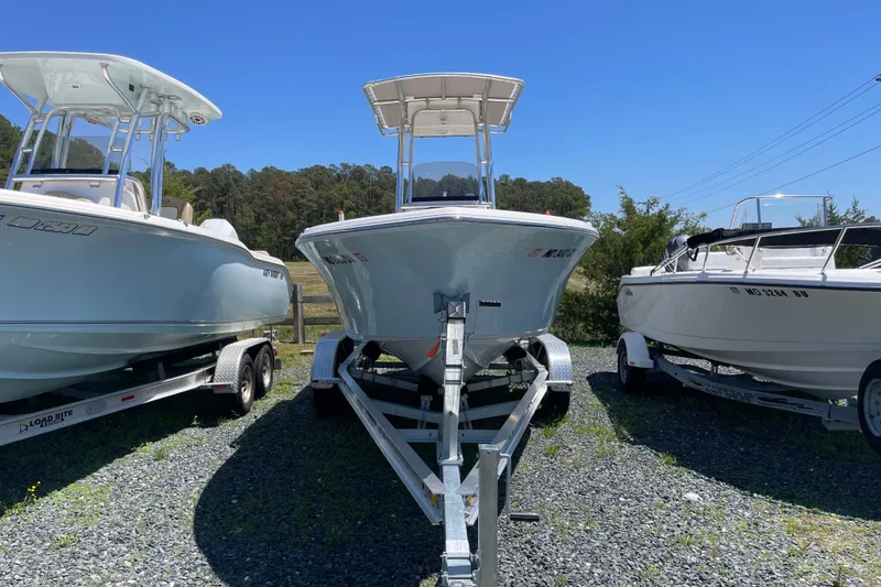 Slide: The Image of 2023 Key West 203 FS boat on trailer, flanked by two other boats, under clear blue sky. - 4