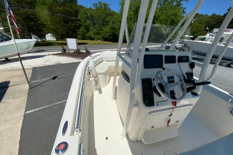 Slide: The Image of 2021 Cobia 220 Center Console boat with steering wheel and control panel, parked outdoors. - 19