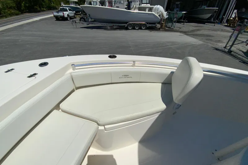 Slide: The Image of 2021 Cobia 220 Center Console boat interior with white seating in a marina setting. - 21