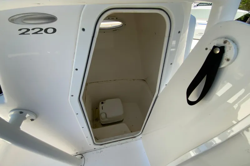 Slide: The Image of 2021 Cobia 220 Center Console boat interior storage compartment with visible portable toilet. - 27