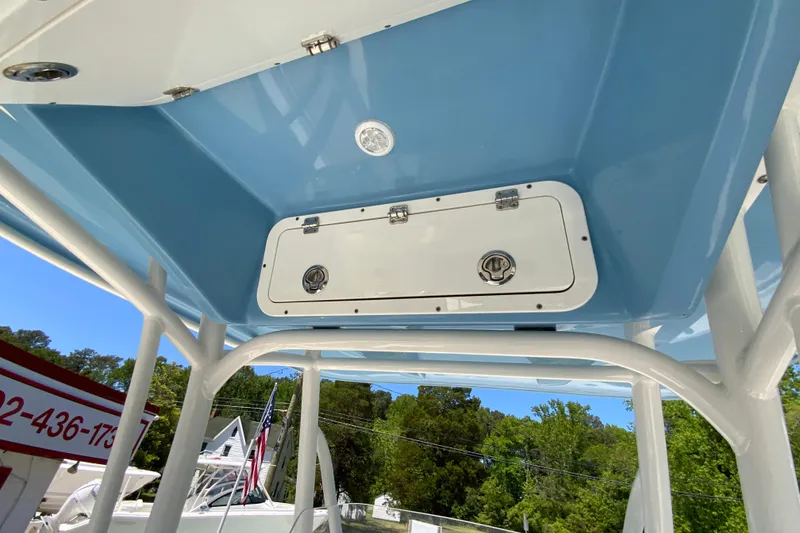 Slide: The Image of 2021 Cobia 220 Center Console boat with blue T-top and storage compartment. - 28