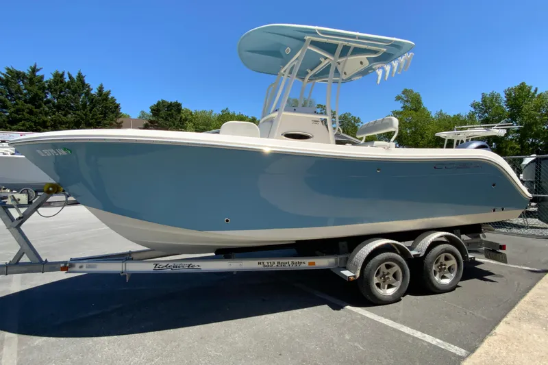 Slide: The Image of 2021 Cobia 220 Center Console boat on trailer, parked outdoors under clear sky. - 6