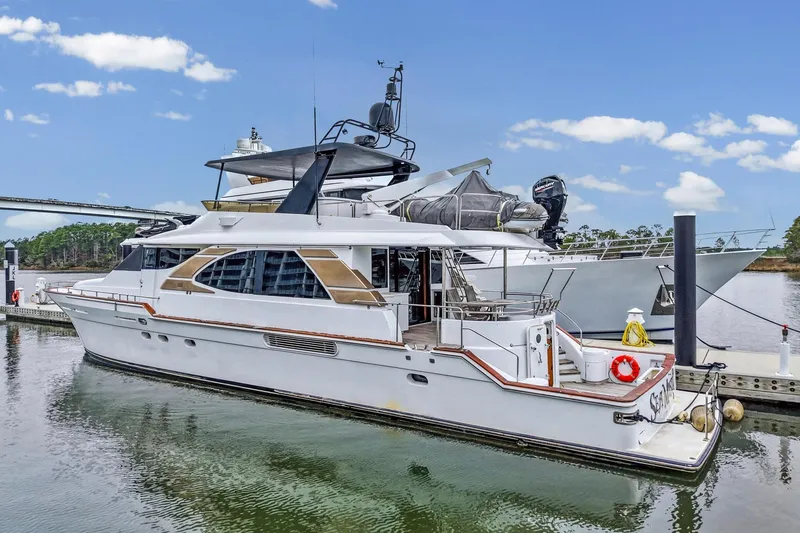Slide: The Image of Luxury 2004 Queenship 76 Baretta yacht docked at marina under clear blue sky. - 2