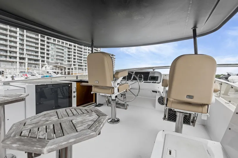 Slide: The Image of Flybridge of 2004 Queenship 76 Baretta yacht with helm chairs and wooden tables. - 31