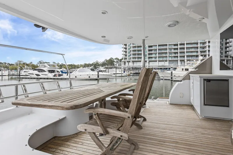 Slide: The Image of Luxury yacht deck with wooden table and chairs, overlooking marina. Queenship 76 Baretta, 2004 model. - 32