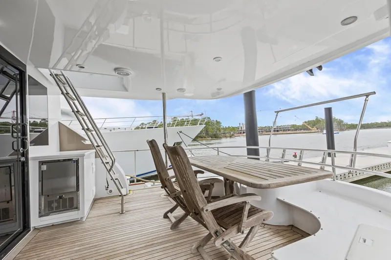 Slide: The Image of Luxurious 2004 Queenship 76 Baretta yacht deck with wooden chairs and scenic waterfront view. - 33