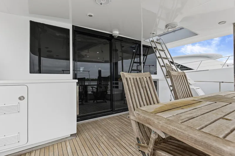 Slide: The Image of Luxury yacht deck with wooden furniture, glass doors, and ladder; Queenship 76 Baretta, 2004 model. - 34