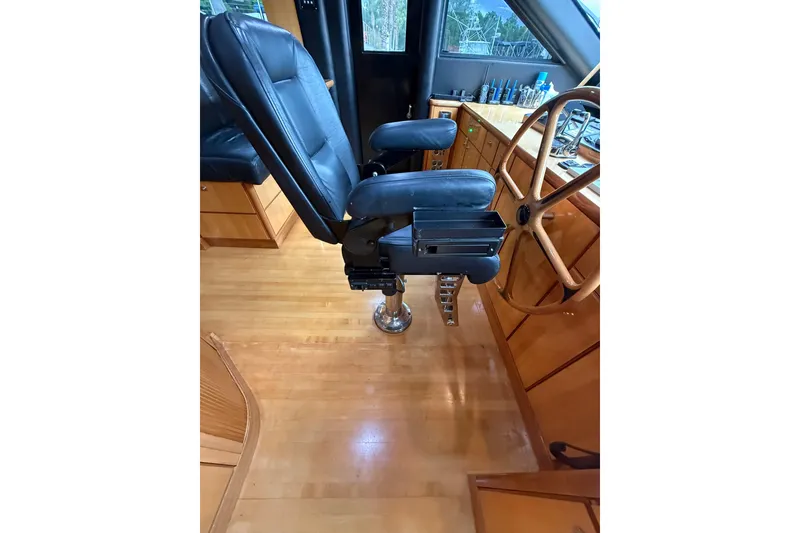 Slide: The Image of Captain's chair and helm of 2004 Queenship 76 Baretta yacht, featuring wooden steering wheel. - 55