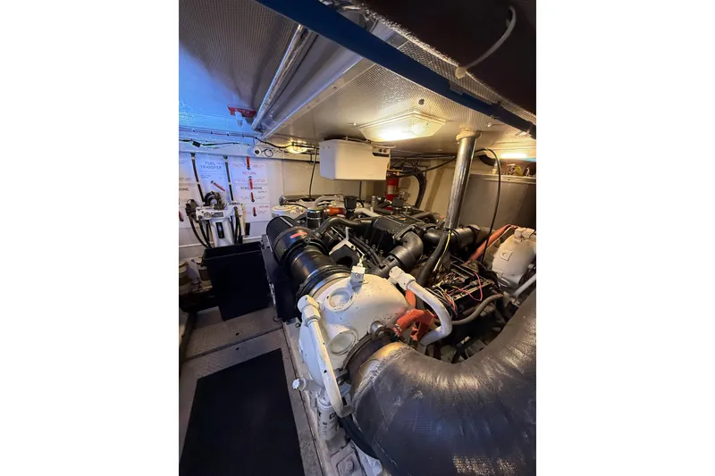 Slide: The Image of Engine room of 2004 Queenship 76 Baretta yacht, showcasing mechanical components and piping. - 69
