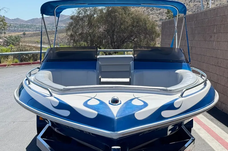 Slide: The Image of 2007 Commander 2300LX boat with blue flame design and canopy, parked outdoors. - 2
