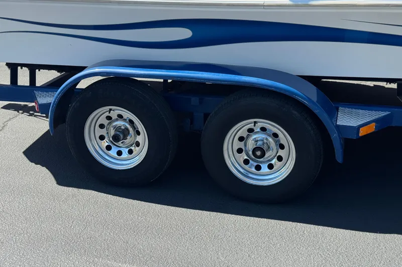 Slide: The Image of Trailer wheels of a 2007 Commander 2300LX boat with blue fender and wave design. - 25