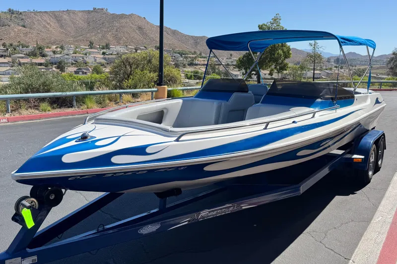 Slide: The Image of 2007 Commander 2300LX boat with blue flame design on trailer, scenic mountain backdrop. - 3