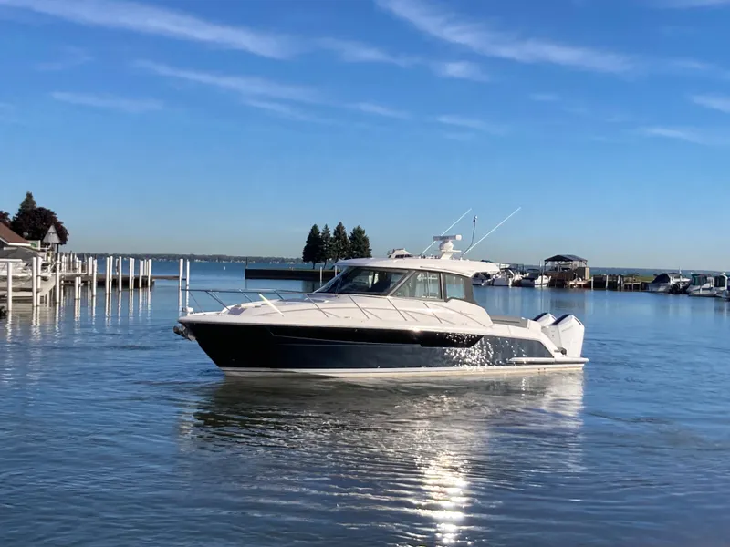 Slide: The Image of 2027 Tiara Yachts 39LE on calm water, surrounded by a harbor with docks. - 49