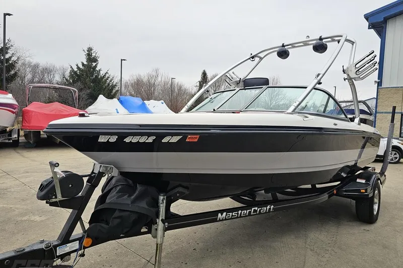 Slide: The Image of 2005 MasterCraft X-2 boat on trailer, parked outdoors with other covered boats nearby. - 15