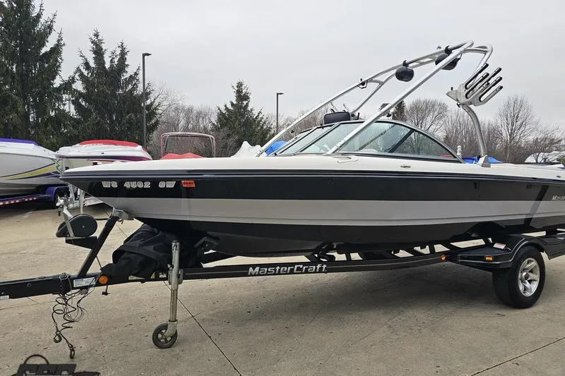 Slide: The Image of 2005 MasterCraft X-2 boat on trailer, parked outdoors with other boats nearby. - 16