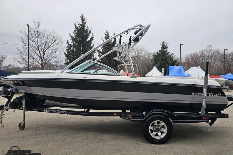 Slide: The Image of 2005 MasterCraft X-2 boat on trailer, parked outdoors, showcasing sleek design and wakeboard tower. - 19