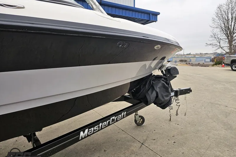 Slide: The Image of 2005 MasterCraft X-2 boat on trailer, parked outdoors near a blue building. - 8