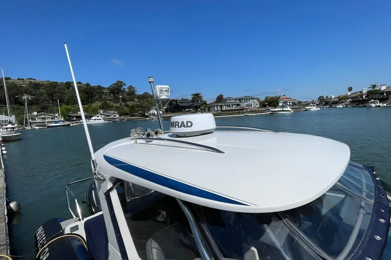 Slide: The Image of 2006 Protector Targa 28 boat docked in a scenic marina with clear blue skies. - 31
