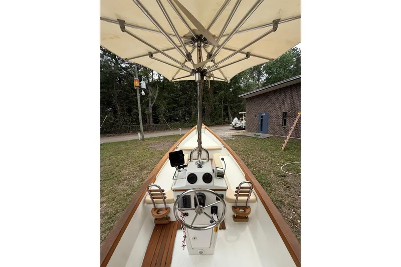 Slide: The Image of 2014 Sea Skiff Caribiana boat interior with steering wheel and canopy, parked outdoors. - 13