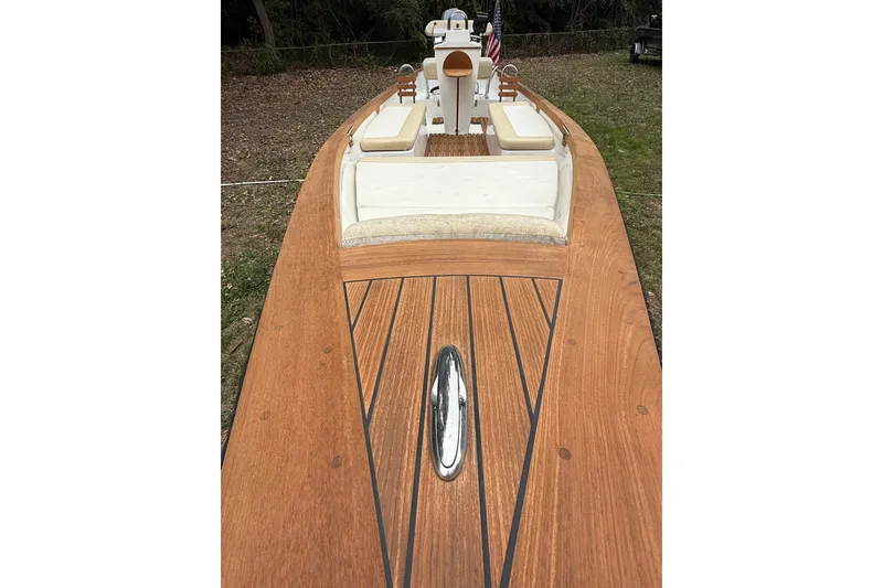 Slide: The Image of 2014 Sea Skiff Caribiana boat with wooden deck and cushioned seating, docked on grass. - 16