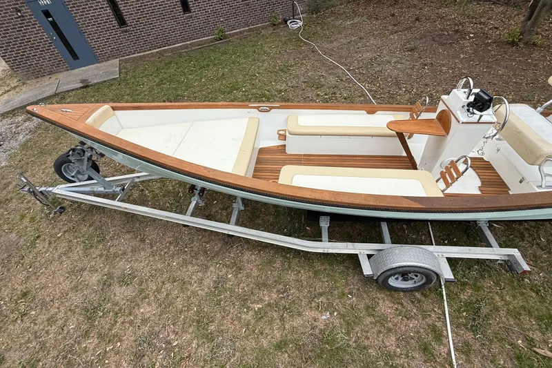 Slide: The Image of 2014 Sea Skiff Caribiana boat on trailer, featuring wooden accents and beige seating. - 4
