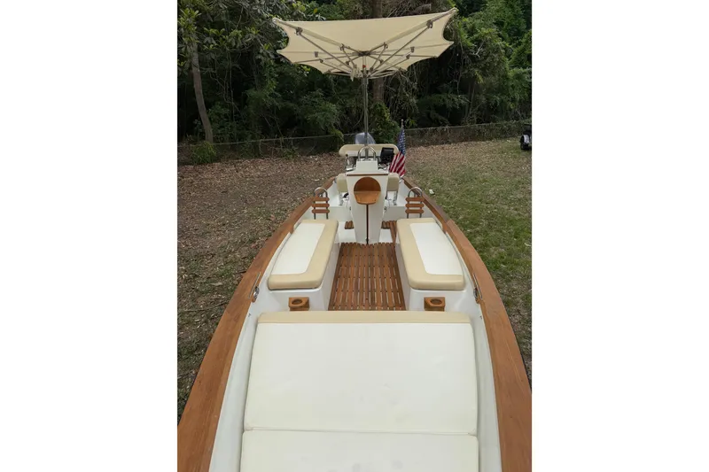 Slide: The Image of 2014 Sea Skiff Caribiana boat with cushioned seating and canopy, set in a wooded area. - 6