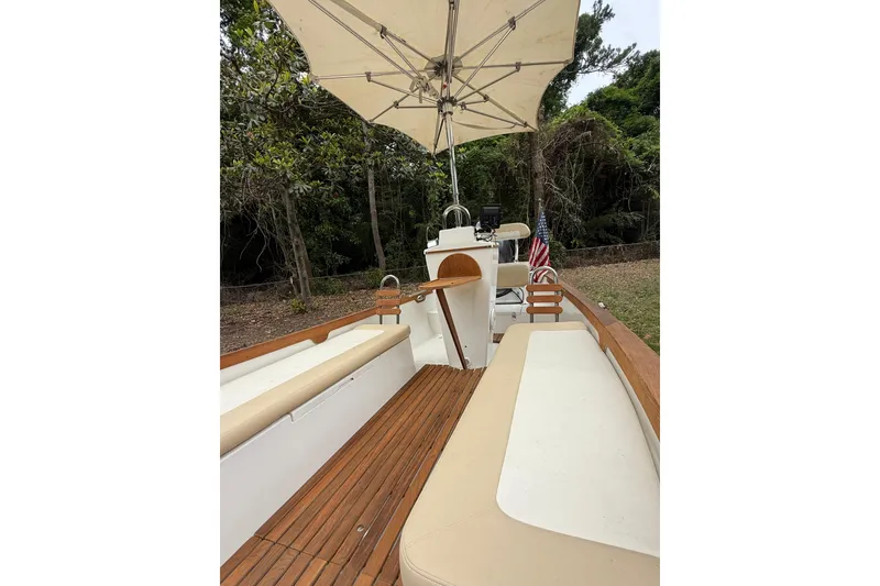 Slide: The Image of 2014 Caribiana Sea Skiff with wooden deck, seating, and umbrella, set in a wooded area. - 7
