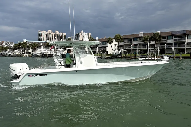 Slide: The Image of 2019 Contender 30 ST boat cruising near waterfront buildings under cloudy skies. - 4
