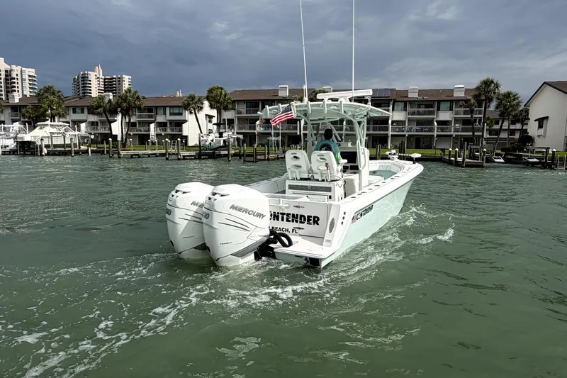 Slide: The Image of 2019 Contender 30 ST boat with twin Mercury engines cruising near waterfront homes. - 7