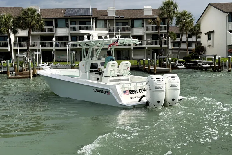 Slide: The Image of 2019 Contender 30 ST boat with twin engines cruising near waterfront homes. - 8