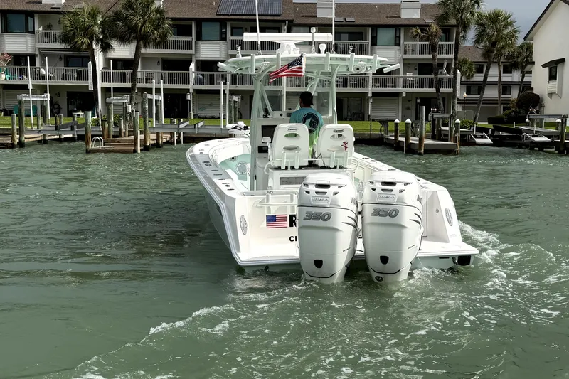 Slide: The Image of 2019 Contender 30 ST boat with twin engines, cruising near waterfront homes. - 9