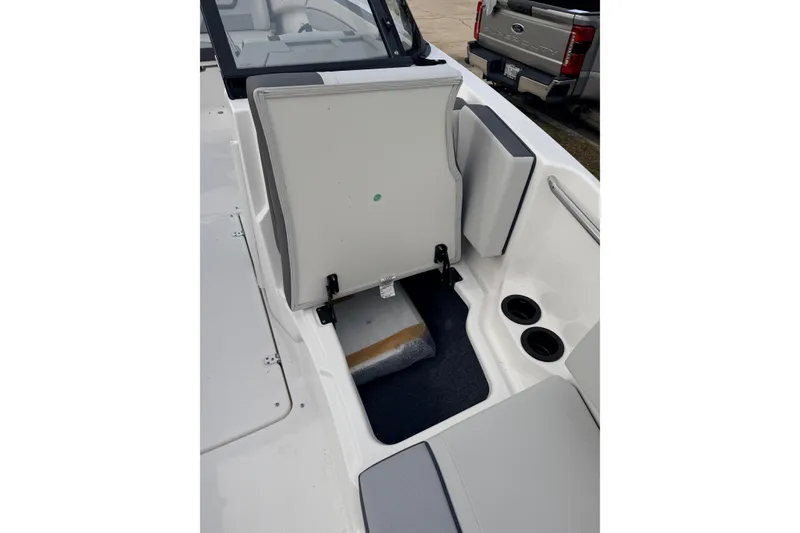 Slide: The Image of 2026 Yamaha Boats AR220 interior storage compartment with open seat and cup holders. - 15