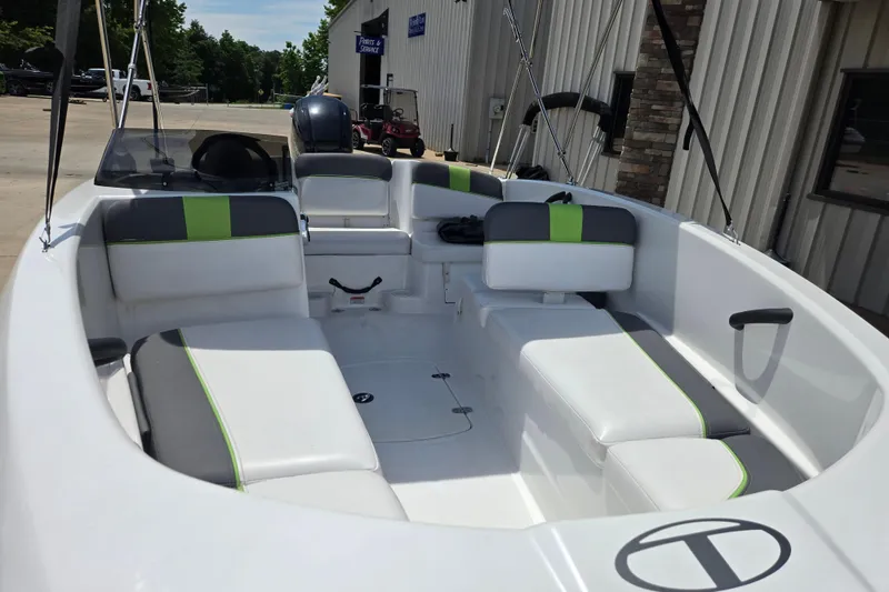 Slide: The Image of 2022 Tahoe T16 boat interior with white and green seating, parked outside a building. - 13