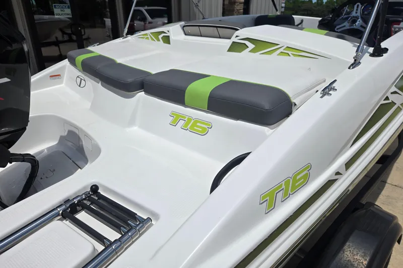 Slide: The Image of 2022 Tahoe T16 boat with green accents and seating, displayed outdoors. - 15
