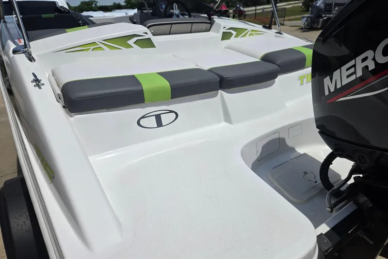 Slide: The Image of 2022 Tahoe T16 boat with green accents and Mercury engine, docked outdoors. - 16