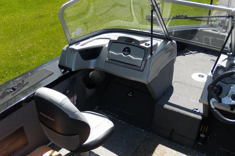 Slide: The Image of 2016 Tracker Targa V-18 WT boat interior with seating and dashboard, on grassy background. - 6