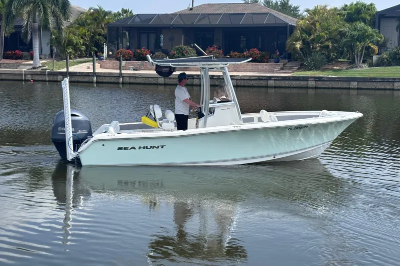 The Image of 2015 Sea Hunt Ultra 211 boat cruising on a calm canal with lush greenery. - 0