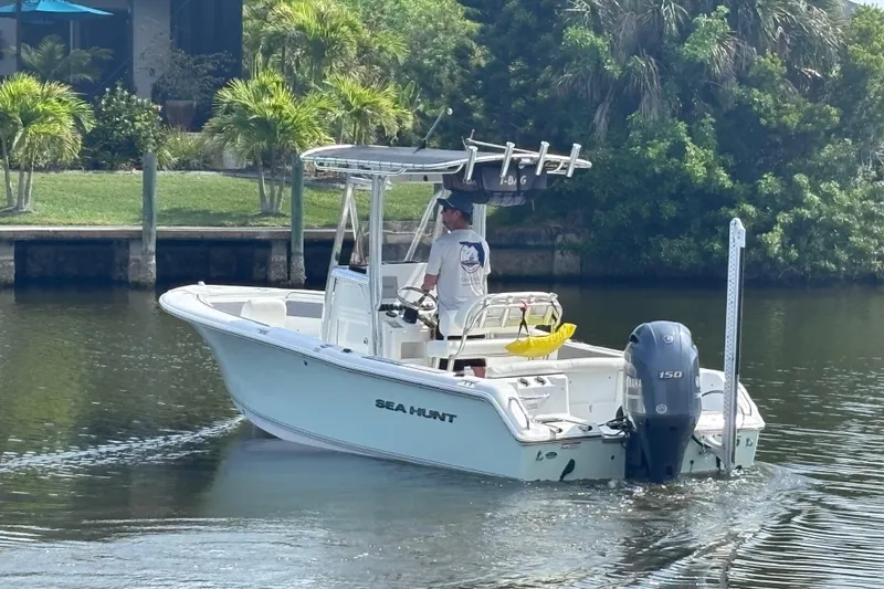 Slide: The Image of 2015 Sea Hunt Ultra 211 boat cruising on a calm waterway with lush greenery. - 1