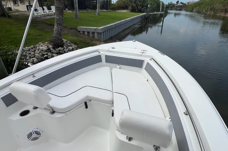 Slide: The Image of 2015 Sea Hunt Ultra 211 boat with white seating, docked by a calm canal. - 2